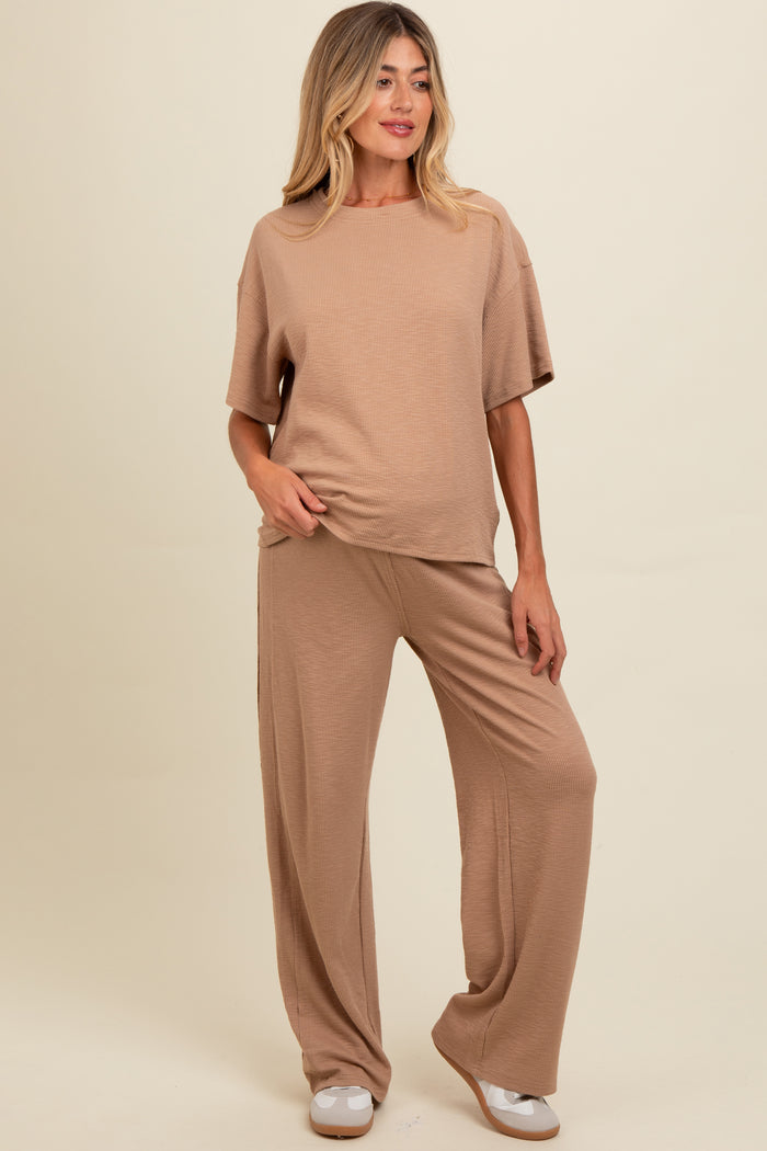 woman wearing a beige maternity loungewear set with a short sleeve top and wide-leg pants
