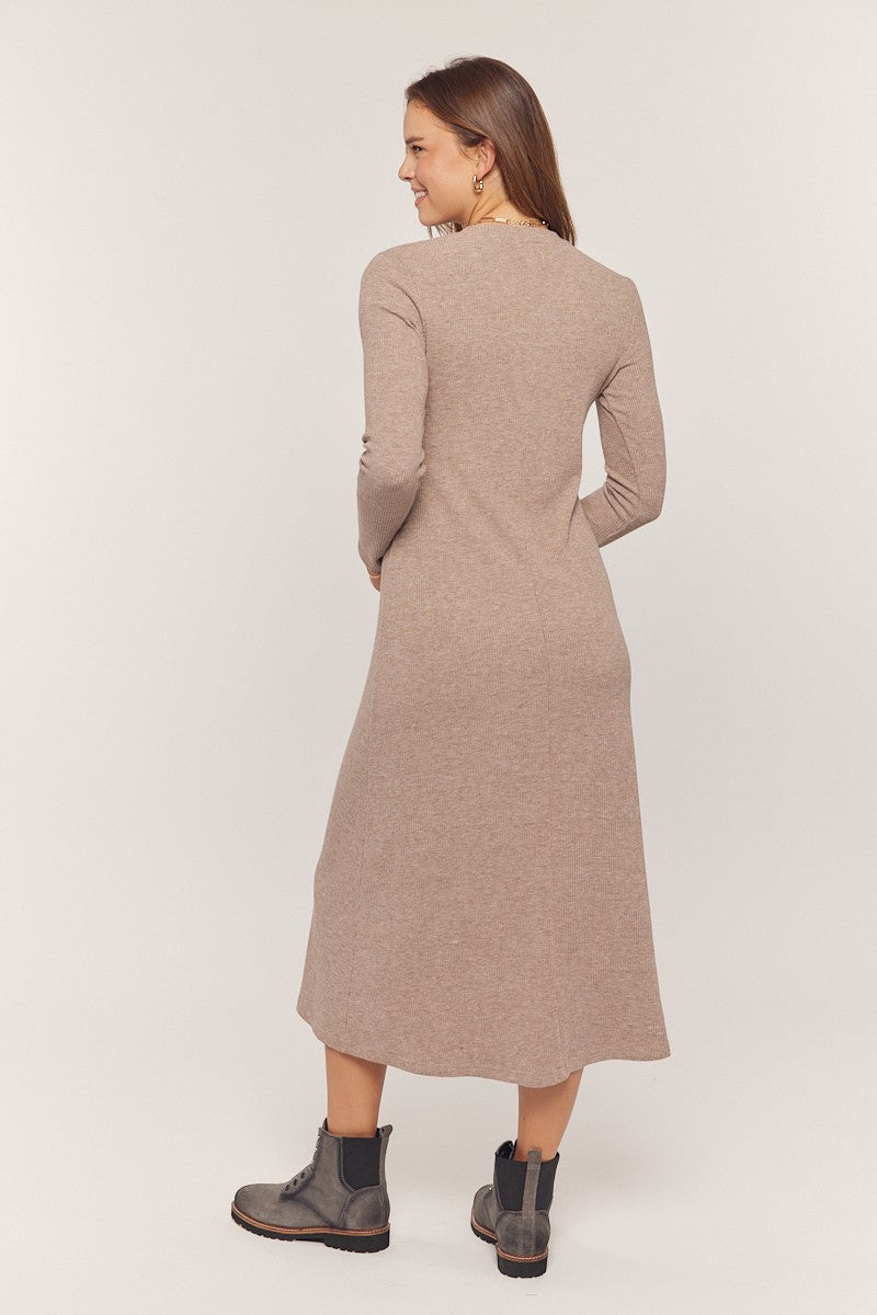 woman wearing a taupe long sleeve knit midi dress and black ankle boots, viewed from the back