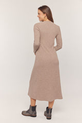 woman wearing a taupe long sleeve knit midi dress and black ankle boots, viewed from the back