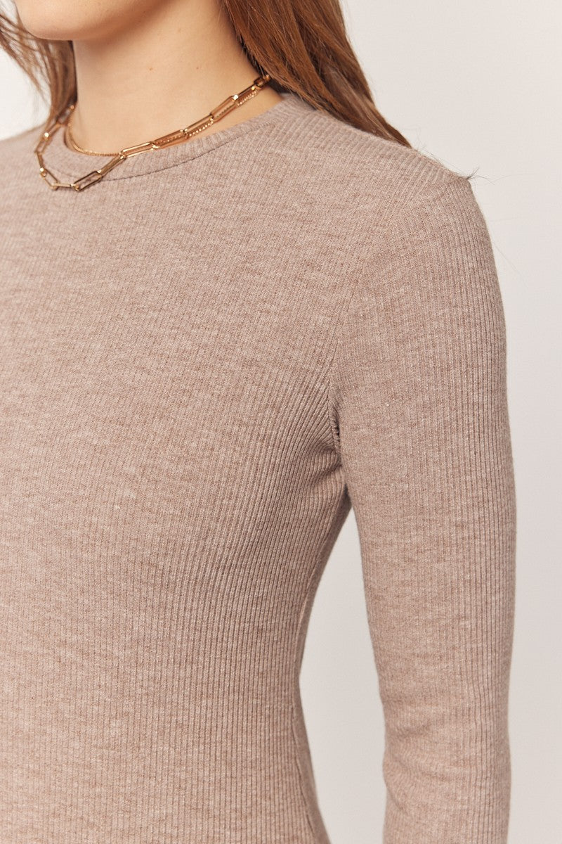 woman wearing a taupe ribbed long sleeve top with a round neckline and a delicate chain necklace
