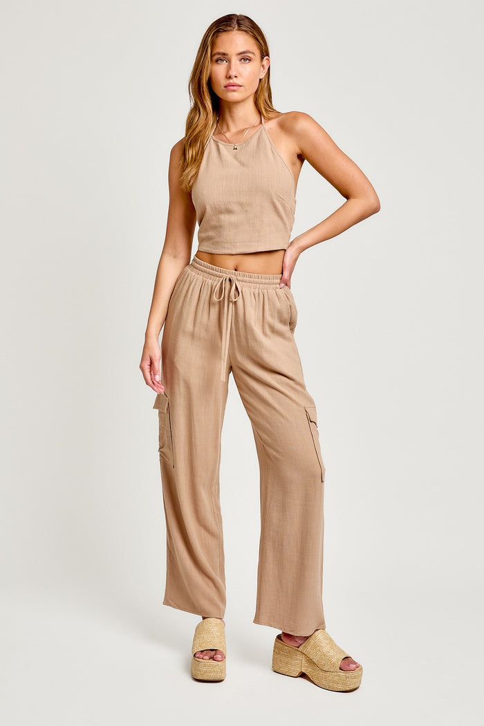 woman wearing a beige cropped tank top and matching wide-leg cargo pants with side pockets and platform sandals