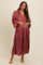 woman wearing a rust-colored maternity dress with pleated details and a v-neckline, holding her baby bump