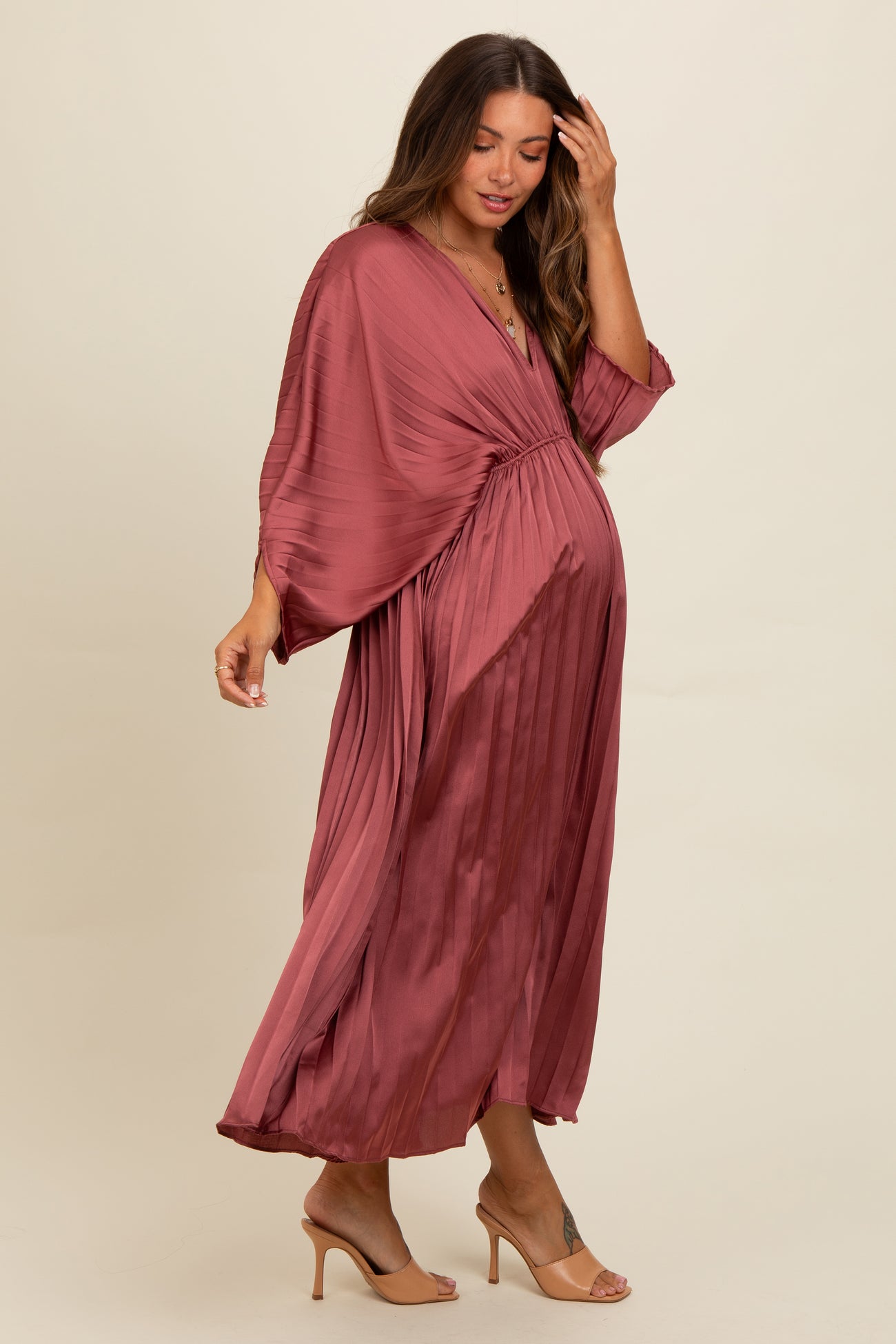 woman wearing a dusty rose maternity dress with pleated details and kimono sleeves, showing her baby bump