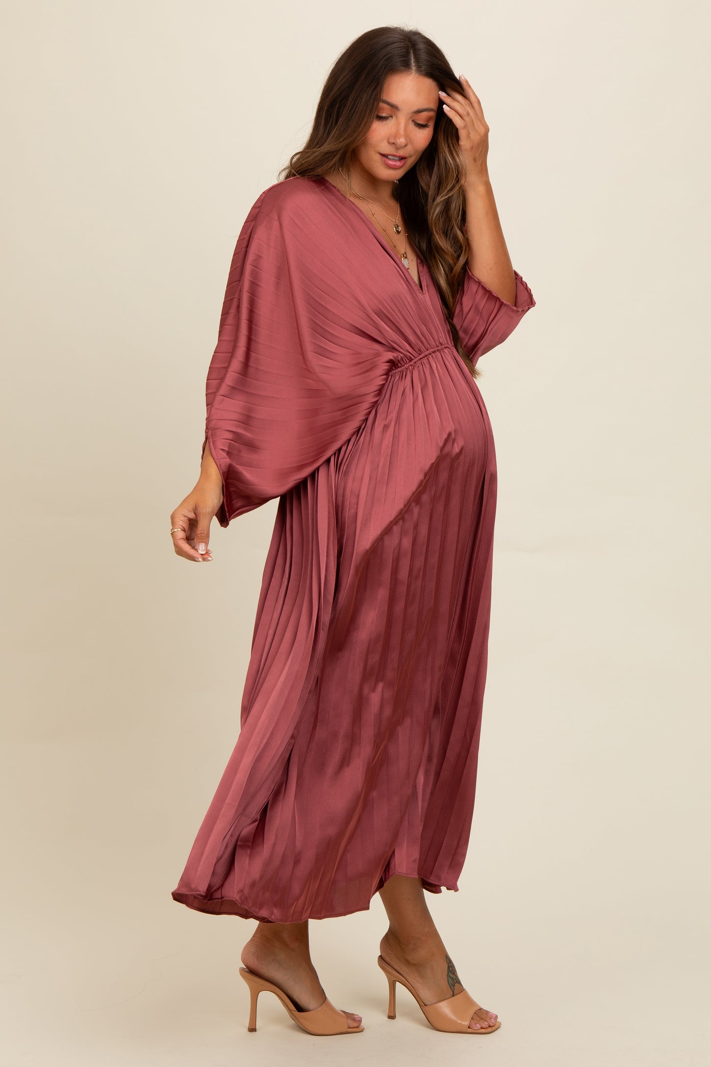 woman wearing a dusty rose maternity dress with pleated details and kimono sleeves, showing her baby bump