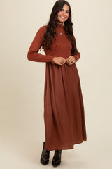 woman wearing a rust ribbed long sleeve knit top with a flowy brown maxi skirt