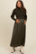 woman wearing a dark green long sleeve maternity dress and a fitted sweater, holding her baby bump