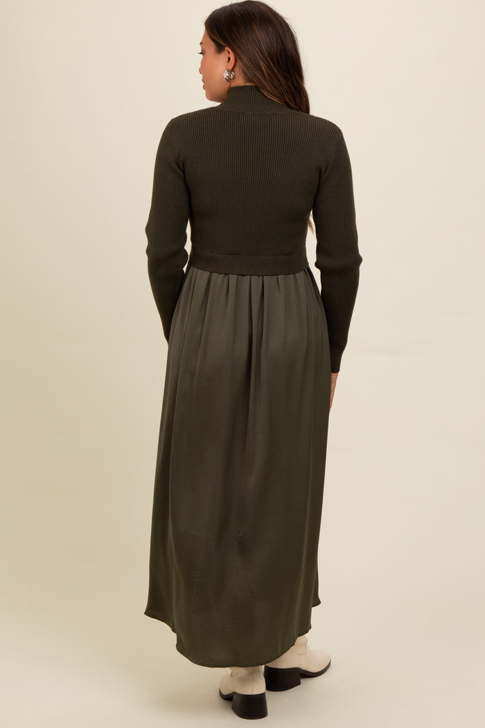 woman wearing a dark green maternity dress with a ribbed top and flowing skirt, viewed from the back