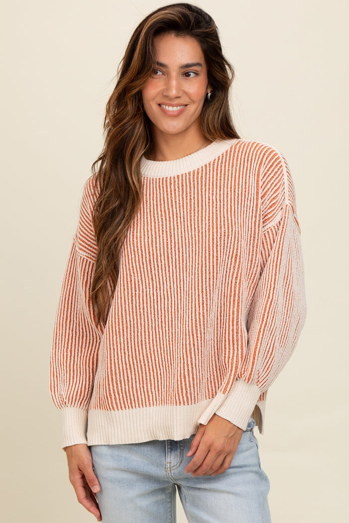 woman wearing a striped orange and cream oversized sweater with balloon sleeves and casual jeans