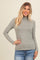 woman wearing a light grey long sleeve mock neck top with a fitted style and casual look