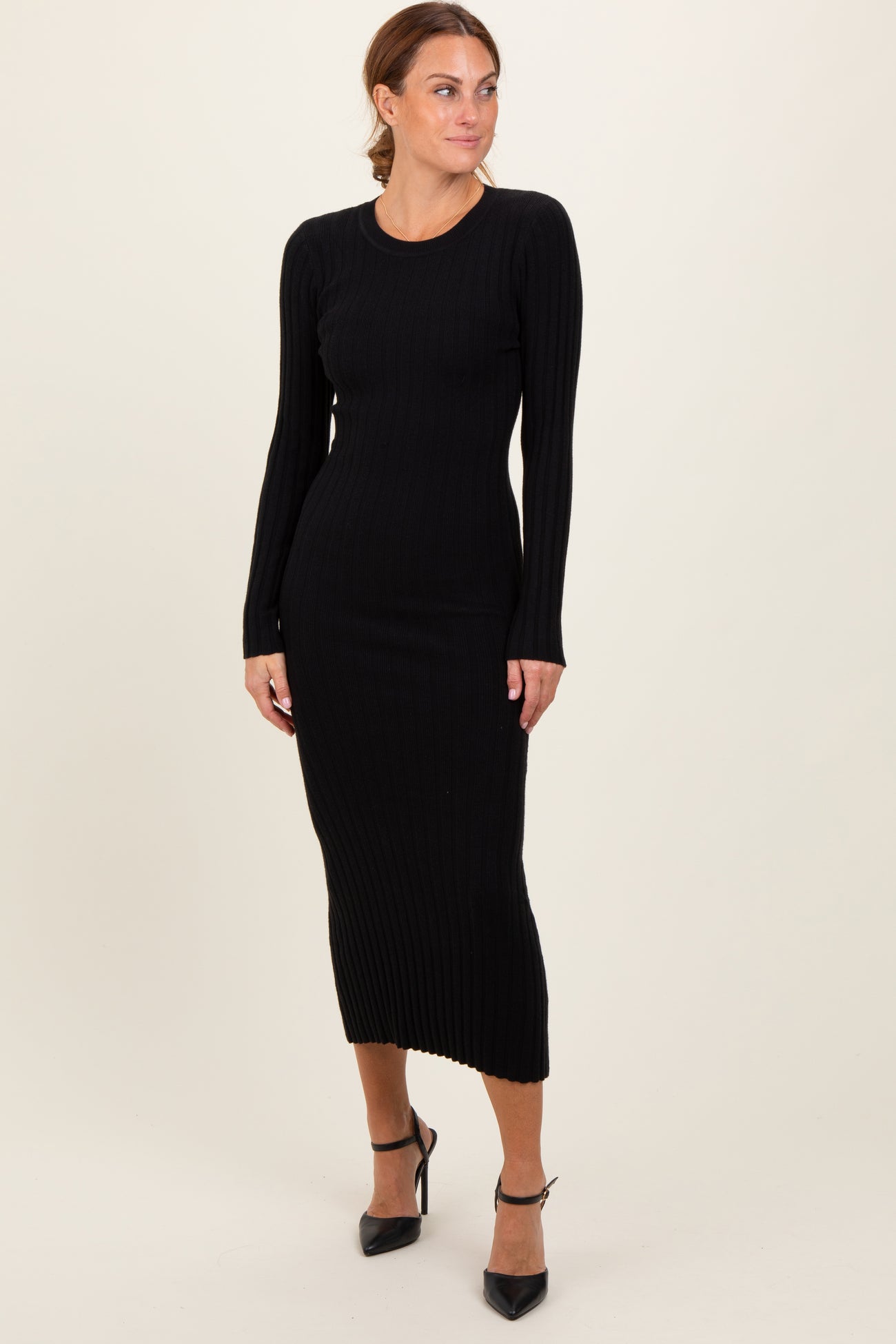 woman wearing a black ribbed long sleeve midi dress with a fitted silhouette and side slit, posing confidently