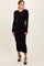 woman wearing a black ribbed long sleeve midi dress with a fitted silhouette and side slit, posing confidently