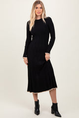 woman wearing a black ribbed knit long sleeve dress with a fitted silhouette and contrasting hemline, paired with ankle boots