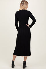 woman wearing a black ribbed knit midi dress with long sleeves and a flared hem, viewed from the back