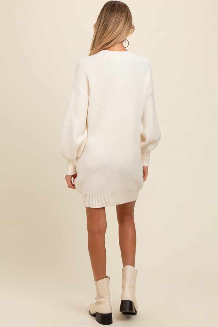 woman wearing an ivory oversized maternity sweater dress with balloon sleeves, viewed from the back
