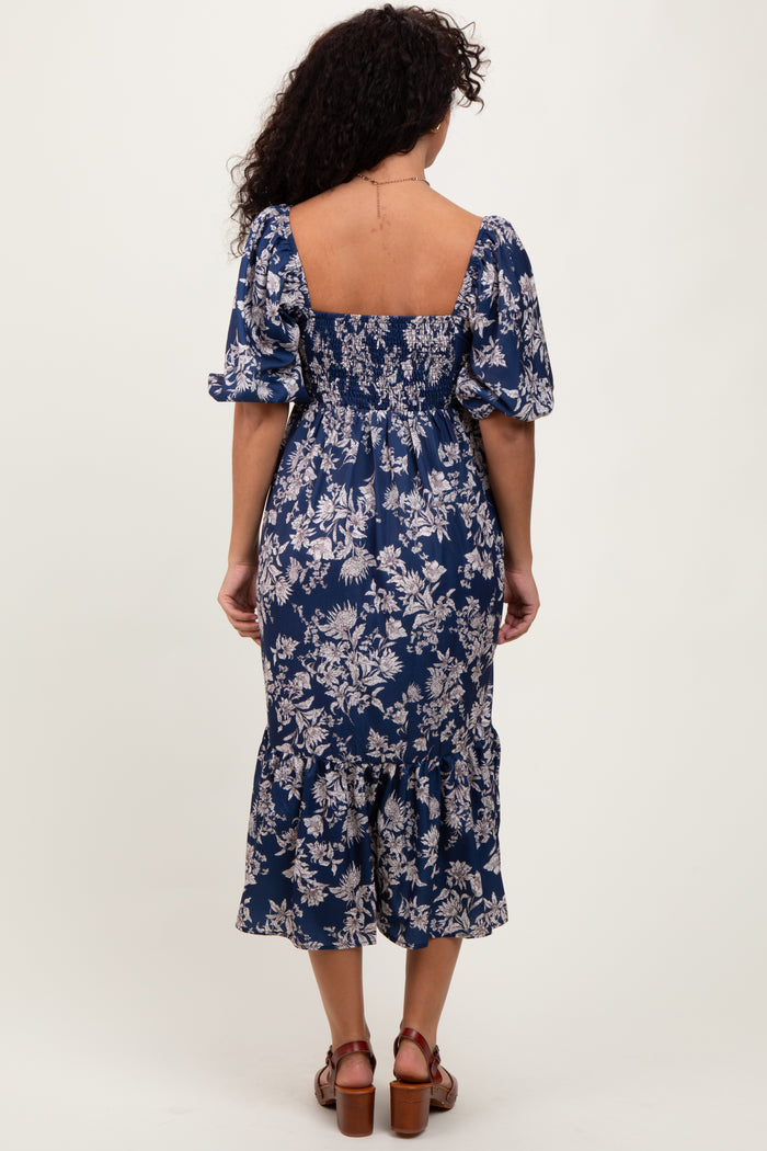 woman wearing a navy blue floral midi dress with puff sleeves and a smocked back
