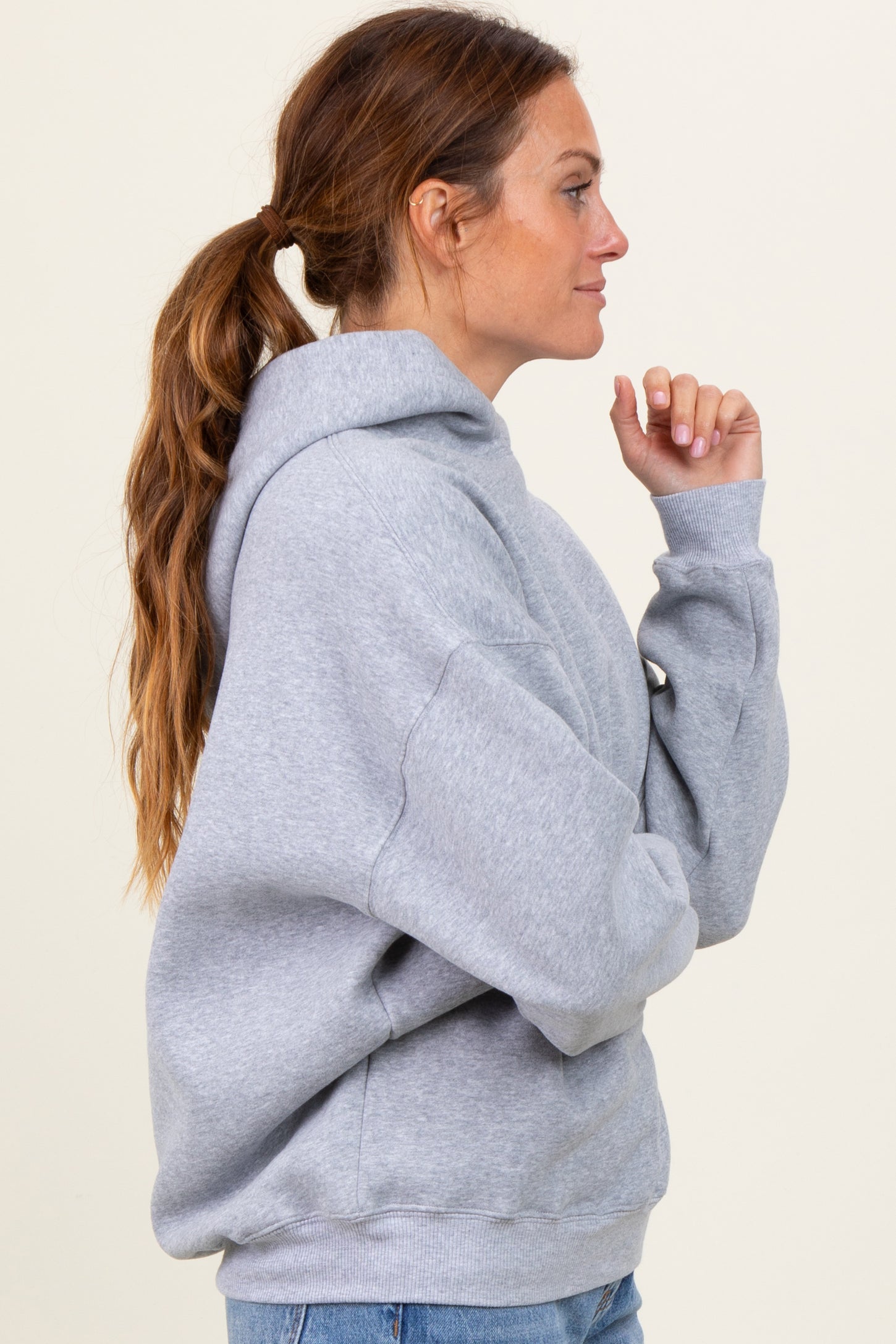 woman wearing a gray oversized hoodie with a front pocket and a relaxed fit, styled with loose denim jeans
