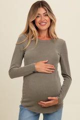woman wearing a ribbed olive green long sleeve maternity top and holding her baby bump