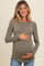 woman wearing a ribbed olive green long sleeve maternity top and holding her baby bump