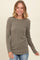 woman wearing a khaki long sleeve ribbed top and smiling at the camera