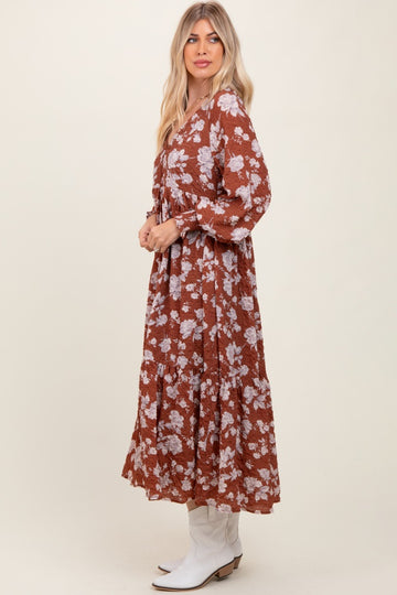 woman wearing a brown floral maxi dress with long sleeves and a flowing skirt, styled with white cowboy boots