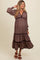 woman wearing a burgundy floral maternity maxi dress with tiered hem and a visible baby bump