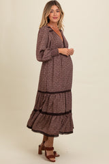 woman wearing a burgundy floral maternity maxi dress with long sleeves and a tiered skirt, showing her baby bump
