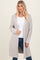 woman wearing a light grey long sleeve open front cardigan over a white top and blue jeans