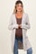 woman wearing a light gray long cardigan over a brown tank top, showing her baby bump, paired with blue jeans