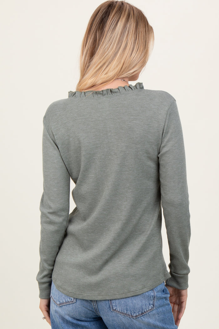 woman wearing a green long sleeve ribbed top with ruffle detail on the neckline, seen from the back