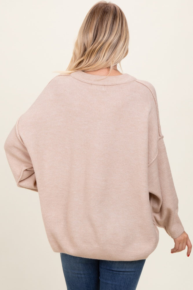 woman wearing a loose-fitting beige oversized sweater with drop shoulders and a relaxed back design