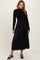 woman wearing a black long sleeve ribbed top and a flowy black midi dress with a fitted waist