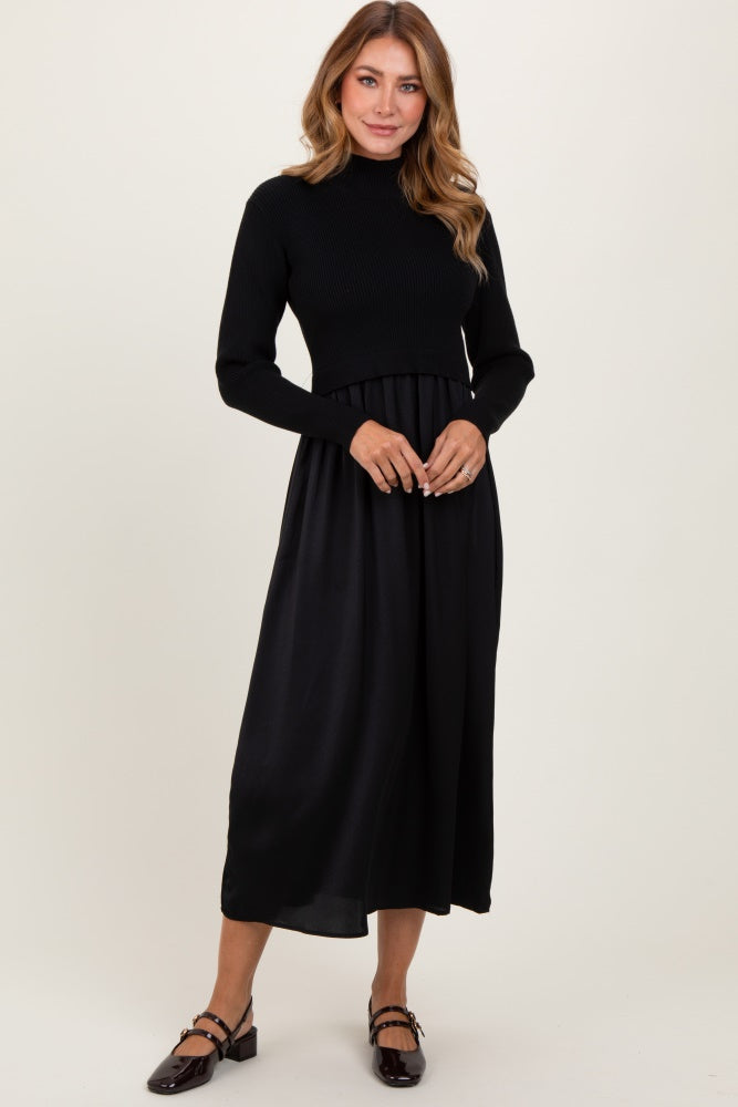 woman wearing a black knit long sleeve dress with a flowy satin skirt and flat shoes