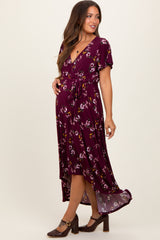woman wearing a maroon floral maternity dress with a wrap style and a tie waist, showcasing a baby bump