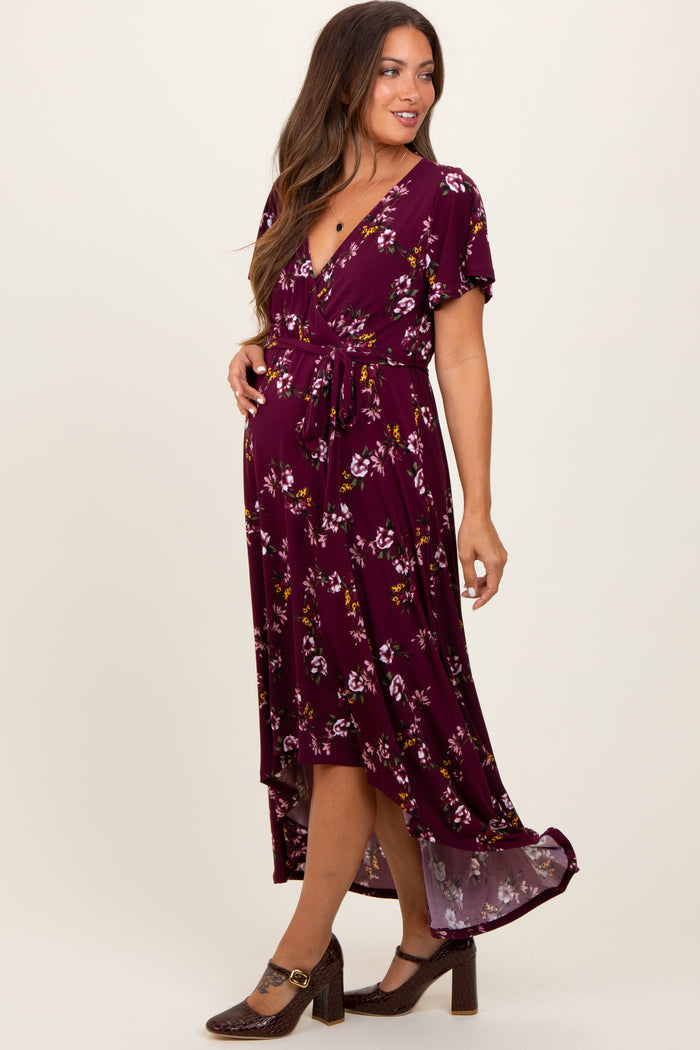 woman wearing a maroon floral maternity dress with a wrap style and a tie waist, showcasing a baby bump