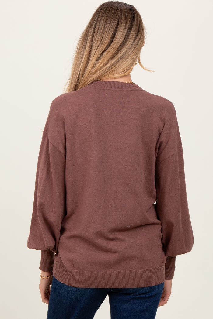 woman wearing a brown maternity sweater with puff sleeves, viewed from the back