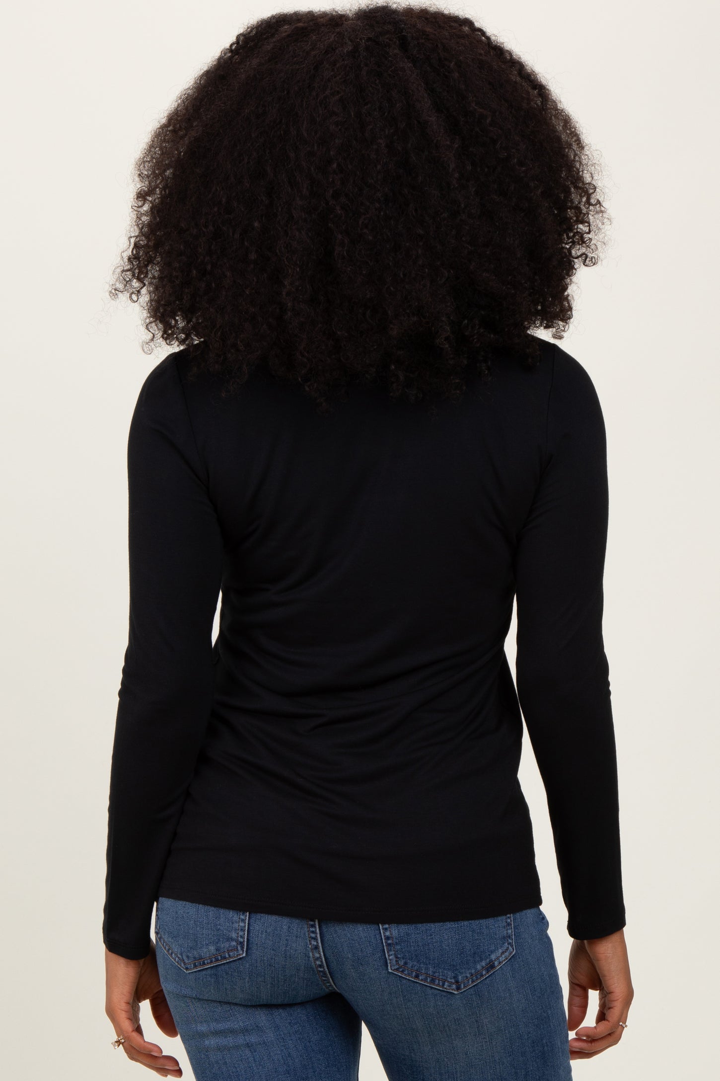 woman wearing a black long sleeve top and blue jeans, viewed from the back