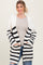 woman wearing a cream and black striped chunky cardigan with pockets over a light gray top and distressed jeans