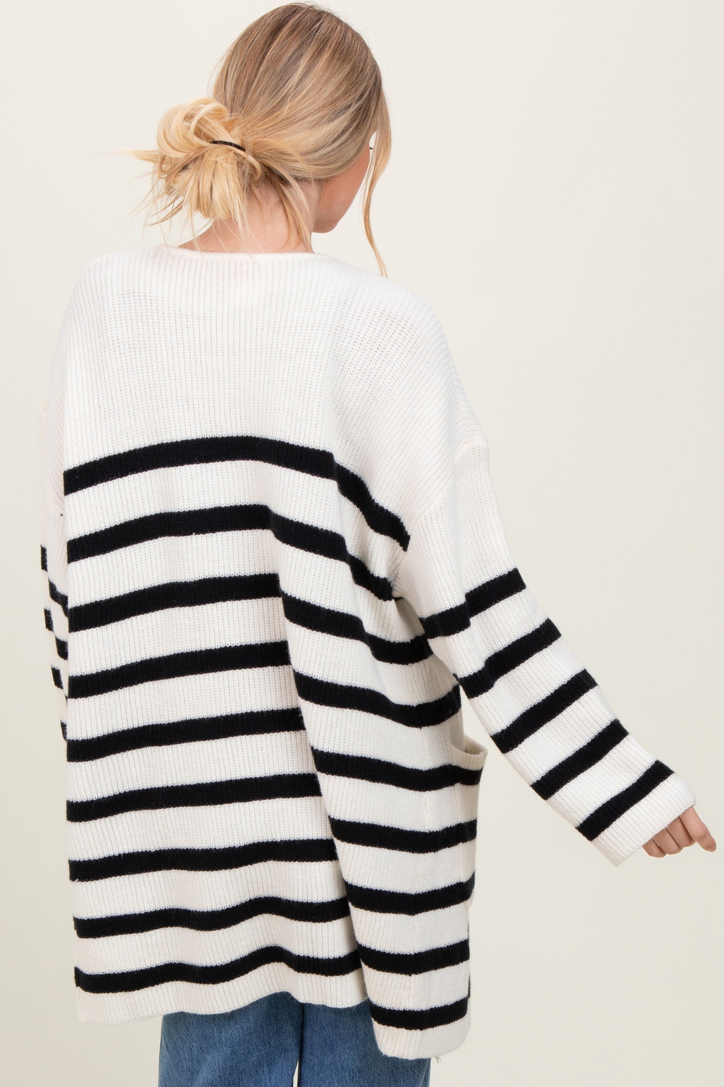 woman wearing a cream and black striped oversized sweater with long sleeves