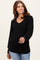 woman wearing a black ribbed long sleeve top with a v-neck and balloon sleeves, smiling and posing with one hand raised