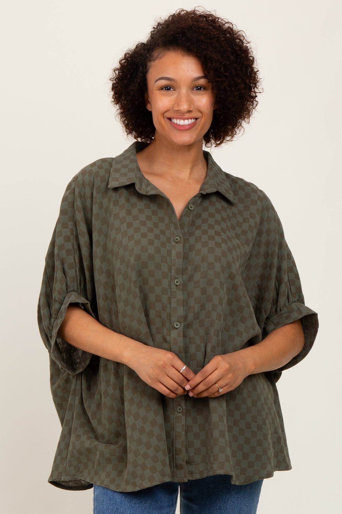 woman wearing an oversized olive green checkered shirt with a button-up front and rolled sleeves