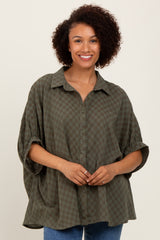 woman wearing an oversized olive green checkered shirt with a button-up front and rolled sleeves
