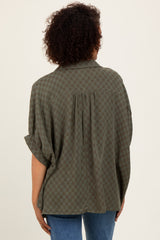 woman wearing an olive green checkered oversized button-up shirt with a pleat detail on the back
