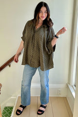 woman wearing a loose-fitting olive green checkered maternity shirt and light blue distressed jeans with black sandals