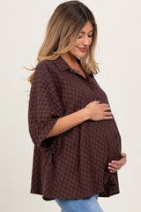 woman wearing a brown checkered maternity shirt with a relaxed fit and holding her baby bump