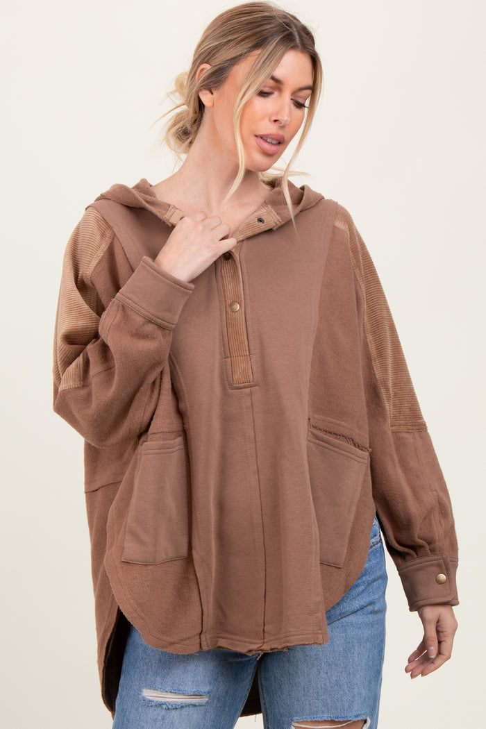 woman wearing a brown oversized hoodie with a henley neckline and front pockets, styled with ripped jeans