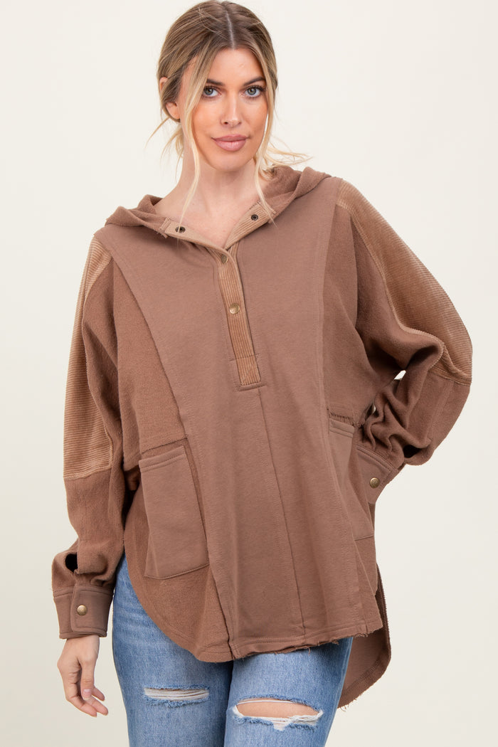 woman wearing a brown oversized hoodie with a henley neckline and front pockets, paired with distressed jeans