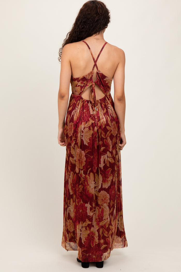 woman wearing a backless sleeveless maxi dress with a floral pattern in red and gold colors