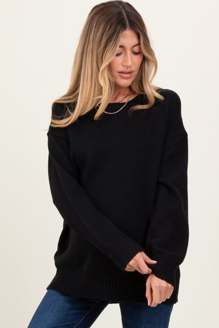 woman wearing a relaxed fit black maternity sweater with long sleeves and ribbed hem