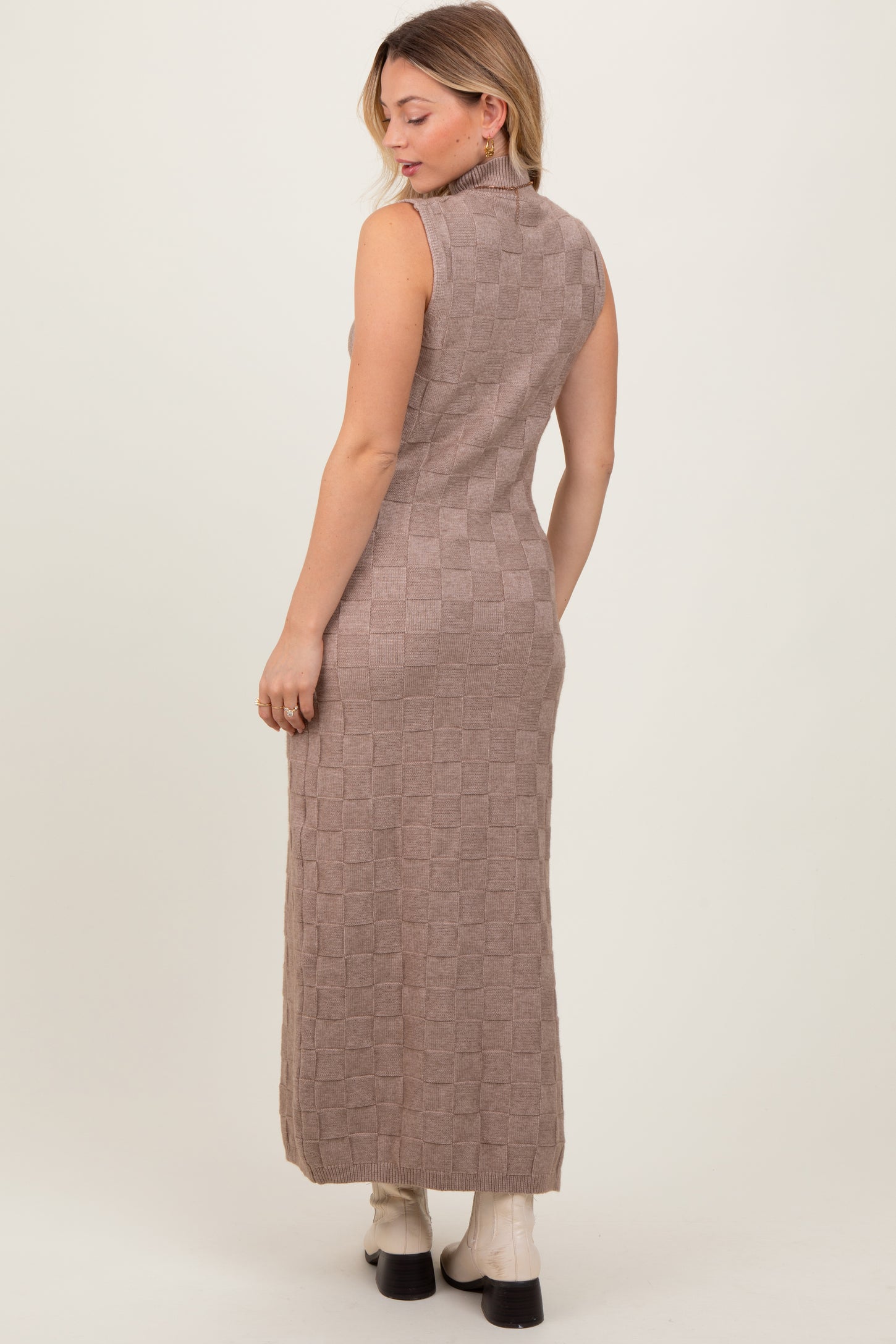 woman wearing a beige sleeveless maxi dress with a checkerboard pattern and side slits, shown from the back