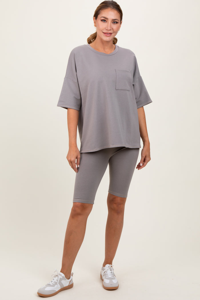 woman wearing a gray oversized t-shirt with a pocket and gray bike shorts, posing with one hand on her hip